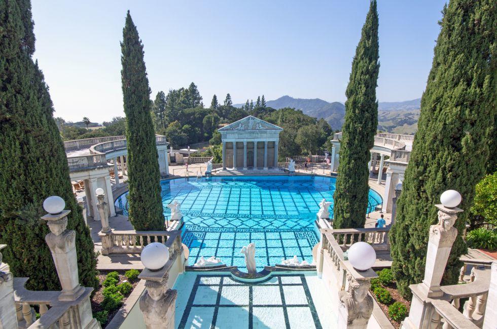 SAN SIMEON, CA, USA April 15, 2013 Hearst Castle grounds, view of the Neptune pool with large Italian cypress and marble inlay tile patio.  