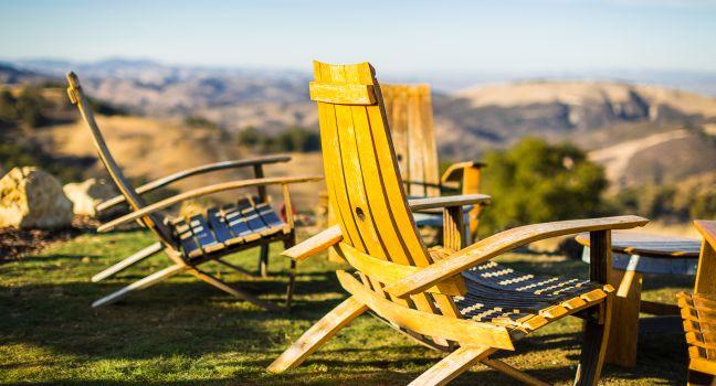 Color shot of adirondack chairs on green grass overlooking Paso Robles wine country at a winery in California