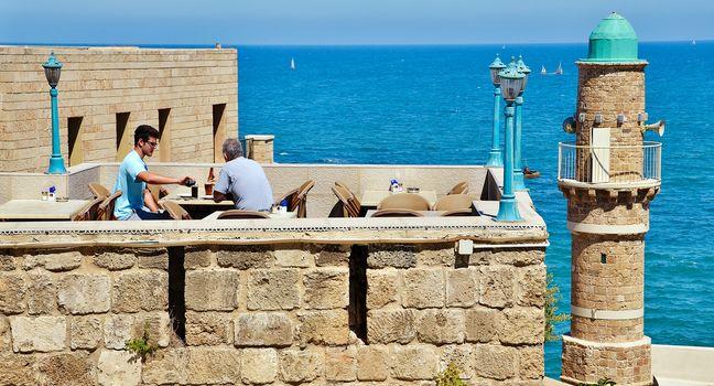 JAFFA, ISRAEL - APR 11, 2014: People eating breakfast with views of the Mediterranean in Jaffa, Tel Aviv, Israel