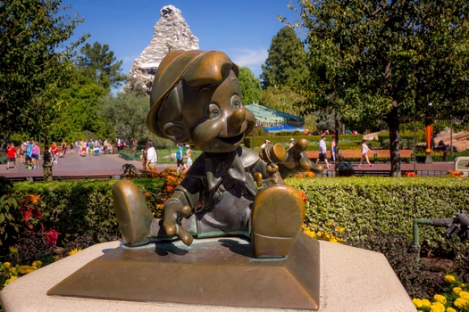 The bronze Pinocchio as a `real boy` greets children to Disneyland. The Matterhorn mountain in the background.