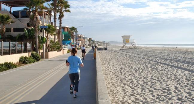 Joggers and cyclists on bicycle path and walkway along a beach; Mission Beach; San Diego, California.