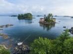 Beautiful calm summer, seascape with boat and houses on tiny forested islands in Sitka Sound on Baranof Island, Alaska.