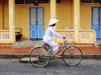 Asian woman with conical hat, riding bike on street in Tay Ninh province, Vietnam.; 