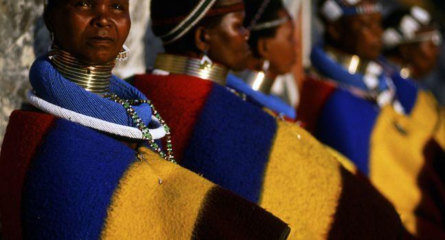 Neck-stretching brass coils announce marrigage as do a beaded jocolo wedding apron that mirrors the primary colors of the decorations hand painted by the mguni-speaking Ndebele.