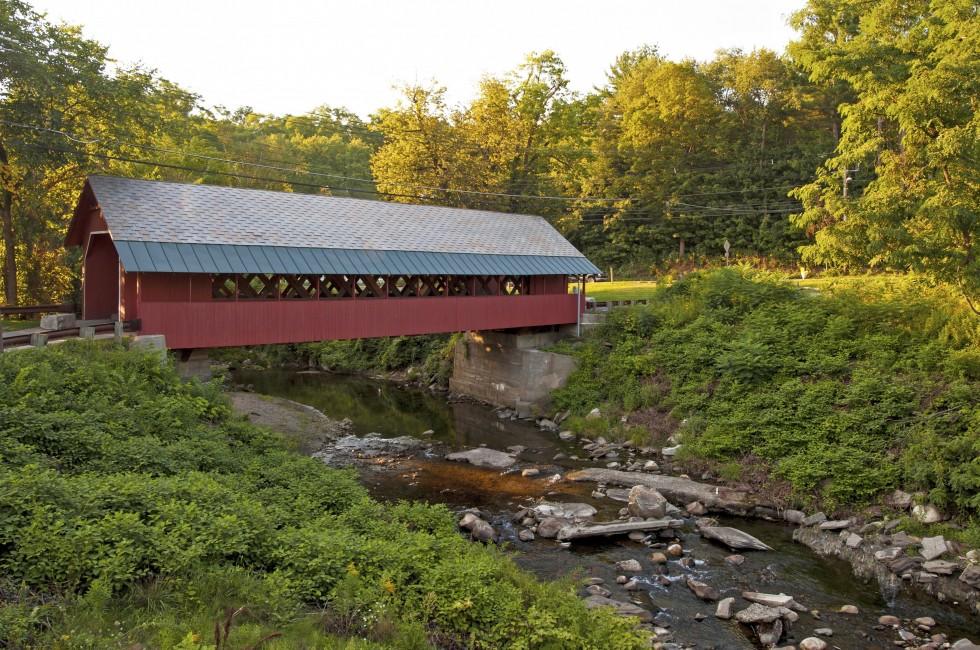 Creamery covered bridge built in 1879 in Brattleboro Vermont. Beautiful historic red covered bridge with a flowing stream of water below it.