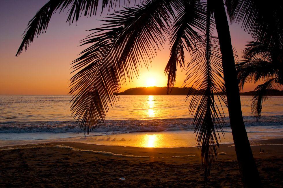 The sun sets behind a little island in Playa Carrillo, Costa Rica.