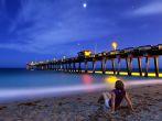 woman sitting on Venice Beach, Florida at night, time exposure; 