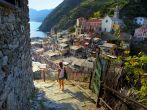 Young woman walking on stairs of small street of Vernazza town. 