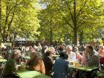 People relax outdoor on a beautiful October day, sitting in the sun, drinking beer and eating Bavarian traditional food in one of the many open air seasonal restaurant (Biergarten) of the Englischer Garten in Munich.