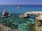 Emerald green sea water with rock arch on Cyprus island;