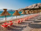Sunshades and orange deck chairs on beach at Baska - Krk - Croatia