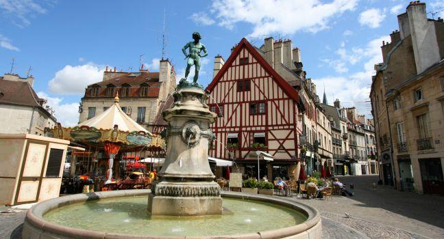 Famous fountain, characteristic houses and colorful carousel in Dijon, Burgundy, France. Place Francois Rude.