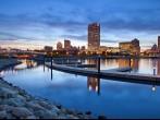 City of Milwaukee skyline. Image of the Milwaukee skyline at twilight with city reflection in lake Michigan and harbor pier.