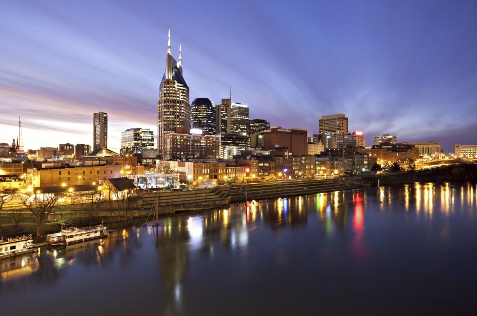 Skyline of Nashville, Tennessee at sunset showing reflections in the Cumberland River.