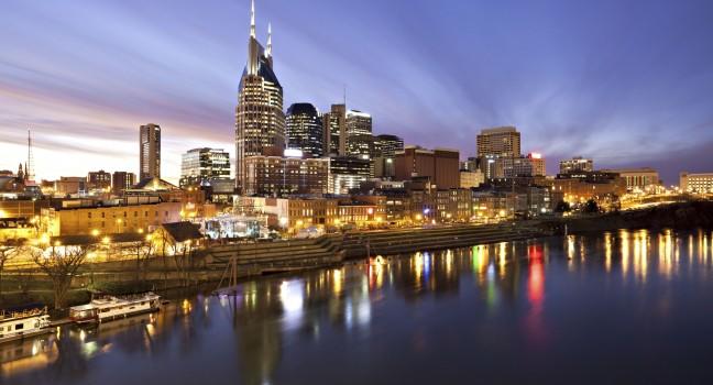 Skyline of Nashville, Tennessee at sunset showing reflections in the Cumberland River.