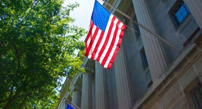 Red white and blue colors of the US flag hang from the side of the Department of Justice in Washington DC.