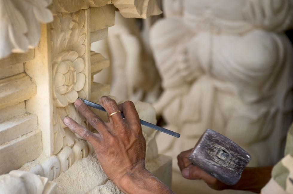 Stone mason at work carving an ornamental relief.