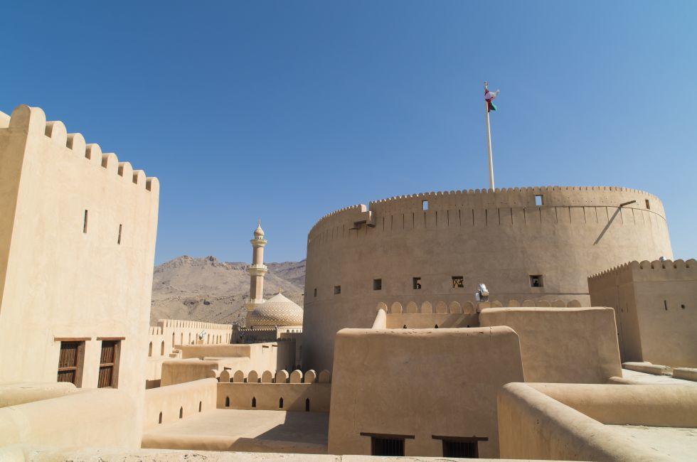Fort Nizwa Oman, with minaret and dom of mosque in background. 