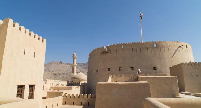 Fort Nizwa Oman, with minaret and dom of mosque in background. 
