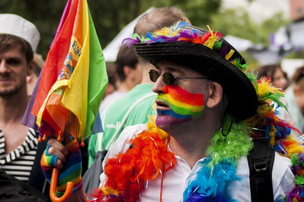BERLIN, GERMANY - JUNE 21, 2014:Christopher Street Day.Crowd of people participate in the parade celebrates gays, lesbians, bisexuals and transgenders.Prominent in the image a elaborately dressed man with garlands and colorful umbrella.