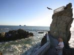 A cliff diver plunges into the pacific ocean.