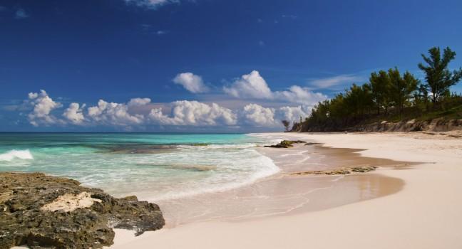 Beautiful white sand beach and turquoise waters and pretty blue sky.  islands of the bahamas.  tropical veiw of the ocean with puffy clouds in the sky.  copy space available;  