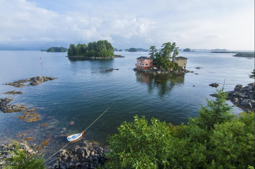 Beautiful calm summer, seascape with boat and houses on tiny forested islands in Sitka Sound on Baranof Island, Alaska.