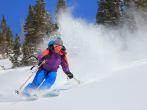 Expert female skier blasting through deep powder snow in the Utah mountains, USA.
