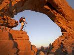 Backpacker standing under magnificent arch in Arches National Park 