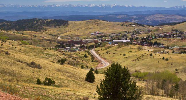 An overlook along a highway looking down into the small gambling town of Cripple Creek, Colorado. Once the hotbed of the gold mining era it is now a casino town. The Sangre De Cristo Mountains are visible in the distance.