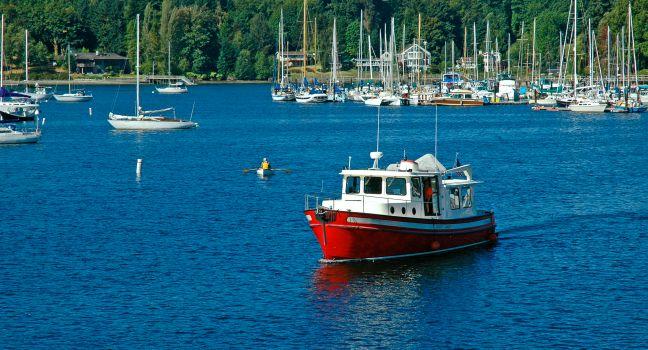 Red boat cruising through the harbor at Bainbridge Island, WA.