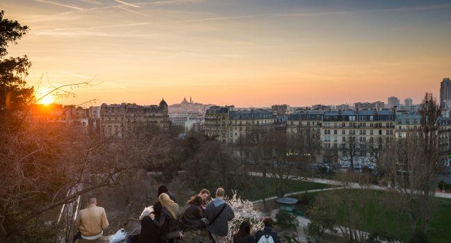 PARIS, FRANCE - MARCH 06, 2014: People enjoying the popular view of Montmartre at sunset from les Buttes Chaumont park