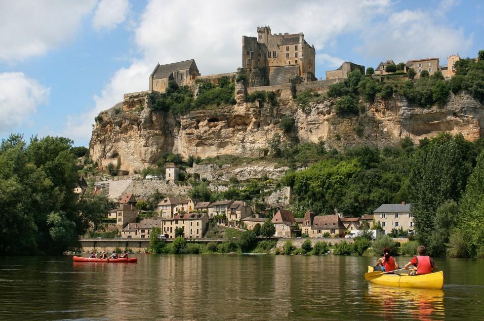 Beautiful landscape with tourists kayaking on river Dordogne and ChÃ¢teau de Beynac in the background as seen in Beynac-et-Cazenac, Southern France