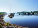 Beautiful water fountain in a river by a bridge, public park in Saguenay, Quebec, Canada; 