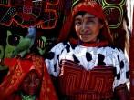 Amongst an archipelago of the San Blas Islands, a Cuna girl bedecked with a  gold nose ring peers though a cleft of fabric, an assortment of inverted appliques known as molas.
