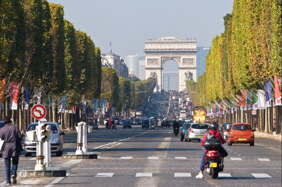 Vehicles travel along Champs Elysees - one of a famous touristic attractions in Paris.