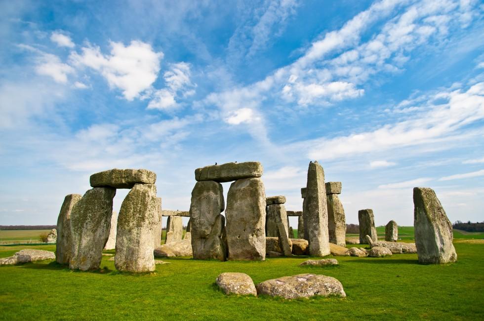 Stonehenge historic site on green grass under blue sky. Stonehenge is a UNESCO world heritage site in England with origins estimated at 3,000BC.