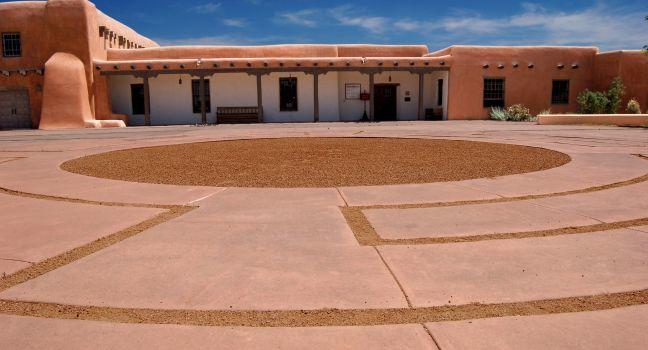 A traditional adobe building located on Museum Hill in Santa Fe, New Mexico. Front plaza area shows unusual paving detail.