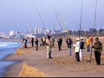 DURBAN, SOUTH AFRICA - JULY 2, 2014: Many unknown early morning fishermen fish on Blue Lagoon beach in Durban South Africa; 