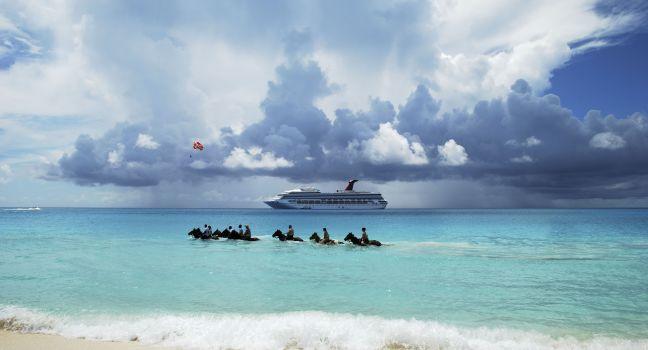 The group of tourists riding horses in Caribbean sea on Half Moon Cay, The Bahamas.