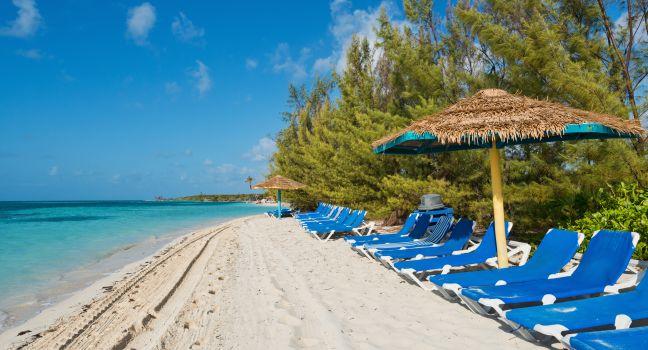 Lounge chairs on a white sand beach, Coco Cay, Bahamas.