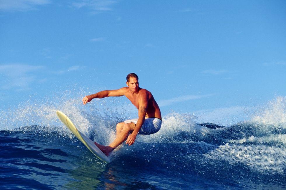 Photo of surfer Chris Gagnon riding a longboard while surfing at Waikiki Beach in Hawaii.
