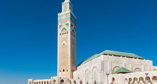 Side view of a modern mosque Hassan II in Casablanca, Morocco. The highest in the world minaret is painted in a traditional Islamic green color. Mosque is located half on land and half on water.; 