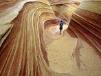 A lone hiker explores the astonishing candy stiped sandstone hidden amongst the geologic folds of the Colorado Plateau, Paria, Arizona