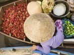Vietnamese fruits seller on floating market - woman selling fruit from her boat in the Mekong river delta, Vietnam.