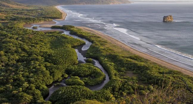 A stunning view of a red sunset in one of the most famous surfing beachs in Central America. Playa Naranjo in the Pacific coast of Costa Rica is home to this iconic rock that gets its name from the whistle it makes when the wind blows. Photo taken o
