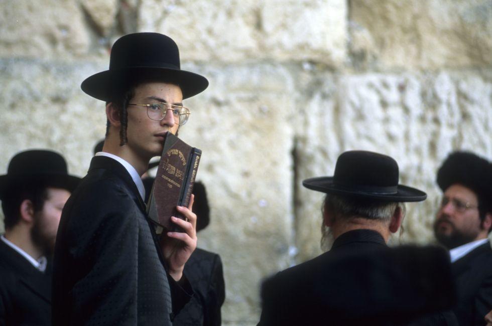 Clutching a siddur prayer book and sporting payos sidelocks, a Jew gathers at the Wiiling Wall where solemn prayers are scribbed and stuffed into the seams of the stone. Jerusalem, Isreal