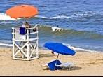 Female lifeguard at her post on Virginia Beach watching a lone swimmer in the ocean surf.