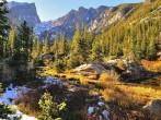 Colorful forest in Rocky Mountain National Park in fall with snow and mountains in background, Colorado, USA; 