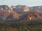 Aerial view of Sedona Arizona with a Hot air balloon soaring thru the red rock landscape.